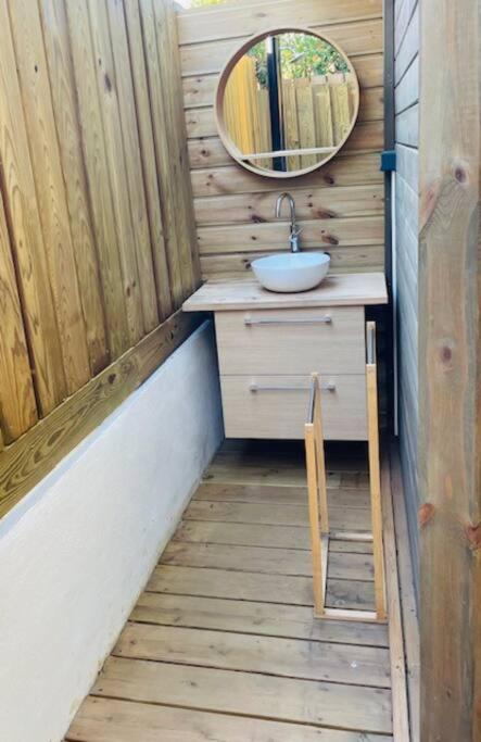 Salle d'eau extérieure en bois avec vasque et miroir rond