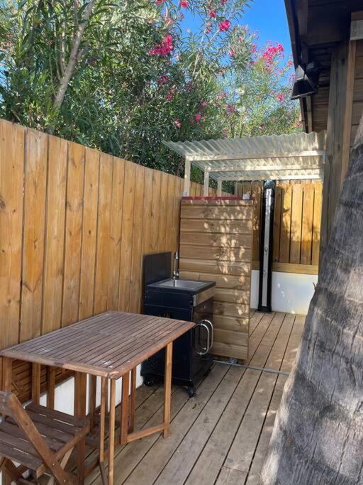 Coin repas extérieur et cuisine d'été sous pergola dans le jardin tropical