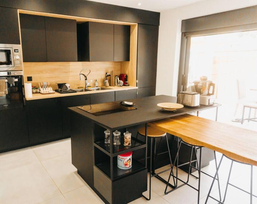 Cuisine noire entièrement équipée avec îlot central et plan snack en bois