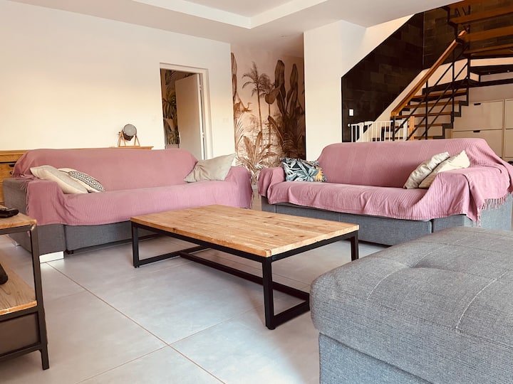 Grand salon convivial avec trois canapés et escalier design