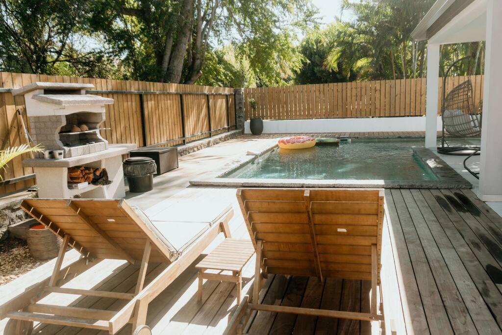 Piscine chauffée, barbecue et transats en bois dans le jardin tropical